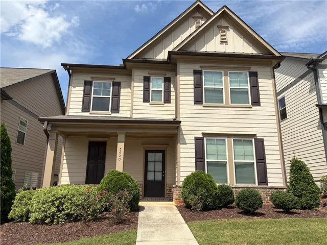 Two-story residence featuring light-colored siding with dark brown shutters, an inviting front porch with columns, and a front entry door with glass panels