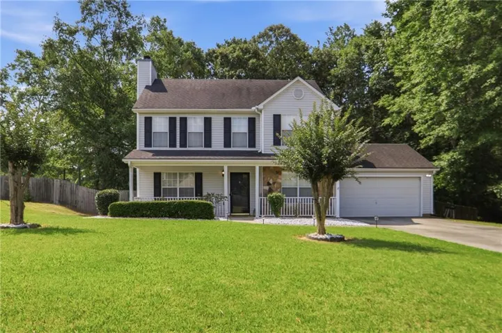 Two-story residence featuring light-colored siding, a covered front porch with white railings, and a two-car garage
