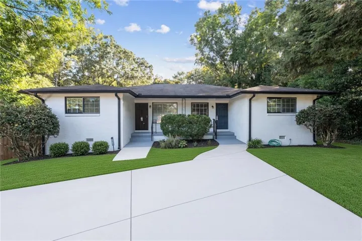 White brick exterior with a dark roofline, black-framed windows, and two distinct entryways