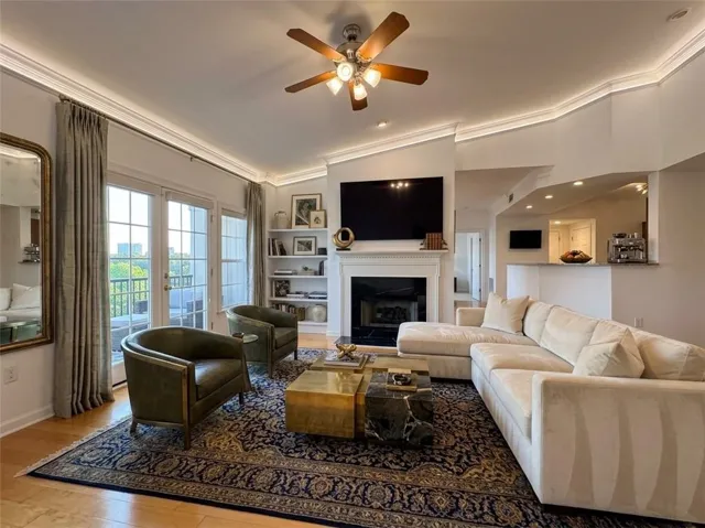 Hardwood flooring with a decorative area rug, crown molding, and a ceiling fan