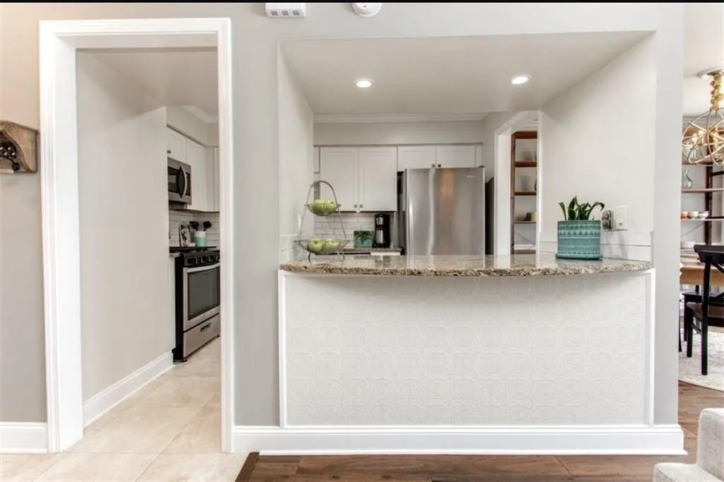Kitchen with white cabinets, light stone counters, backsplash, and stainless steel appliances