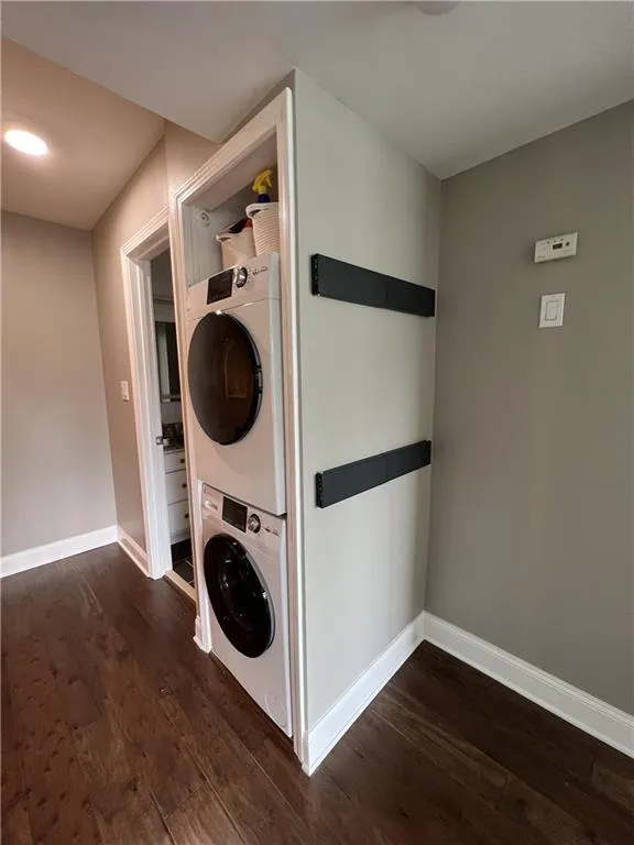 Laundry room featuring dark hardwood / wood-style flooring and stacked washer / dryer