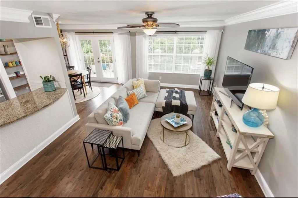 Living room with dark hardwood / wood-style floors, ceiling fan, plenty of natural light, and ornamental molding