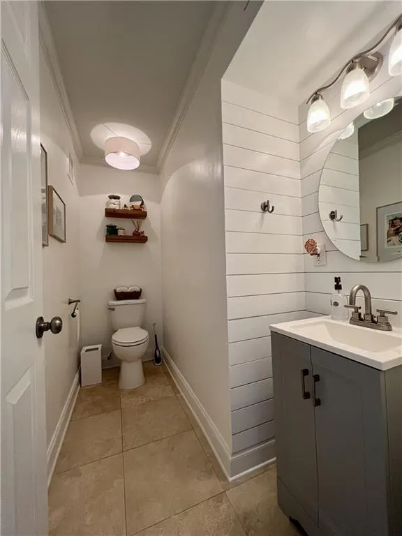 Bathroom with tile floors, crown molding, toilet, and large vanity
