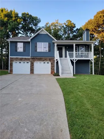 Two-story home with blue siding, stone facade, covered entrance, and an attached two-car garage