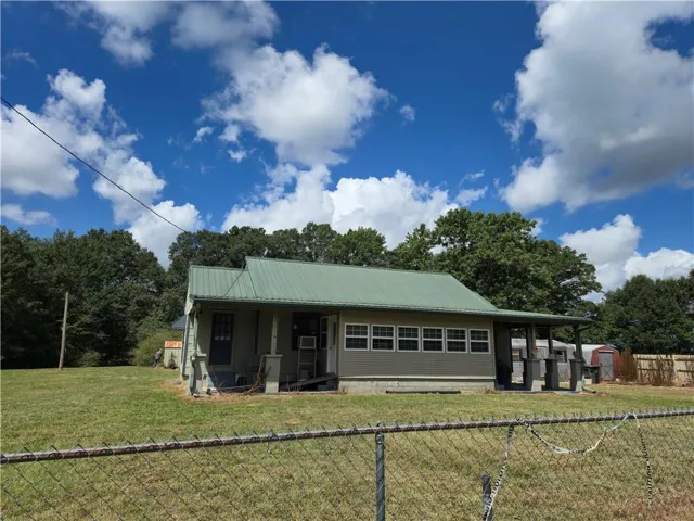 View of front of home featuring a shed, a metal roof, and a fenced backyard