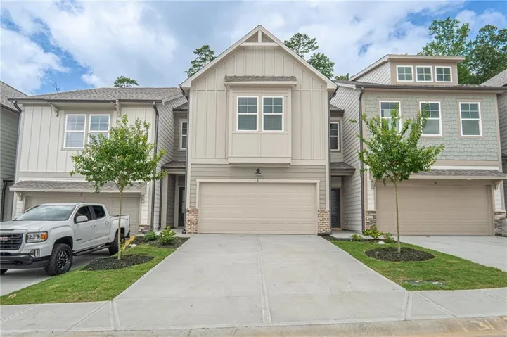 Contemporary townhome exterior featuring light-colored vertical siding and a prominent gable roofline
