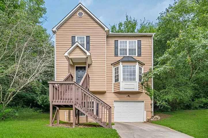 Two-story residence with a front entry deck, bay window, attached garage, and light-toned siding