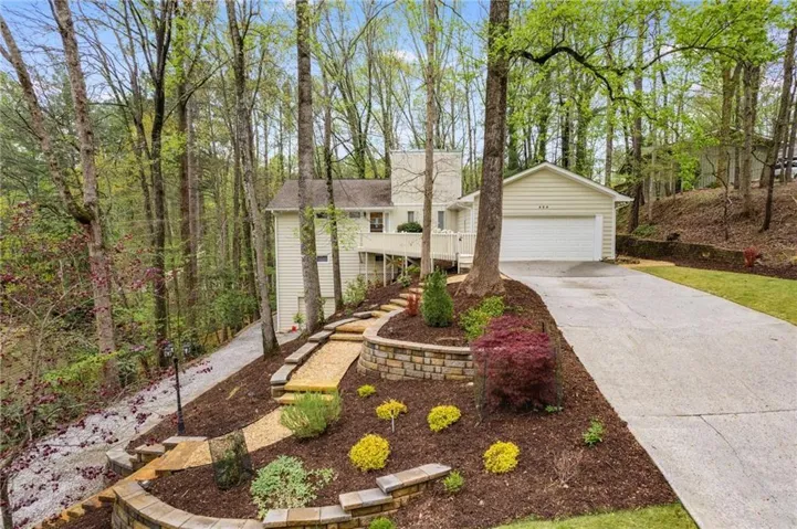 Siding exterior with an attached garage, concrete driveway, and tiered landscaping