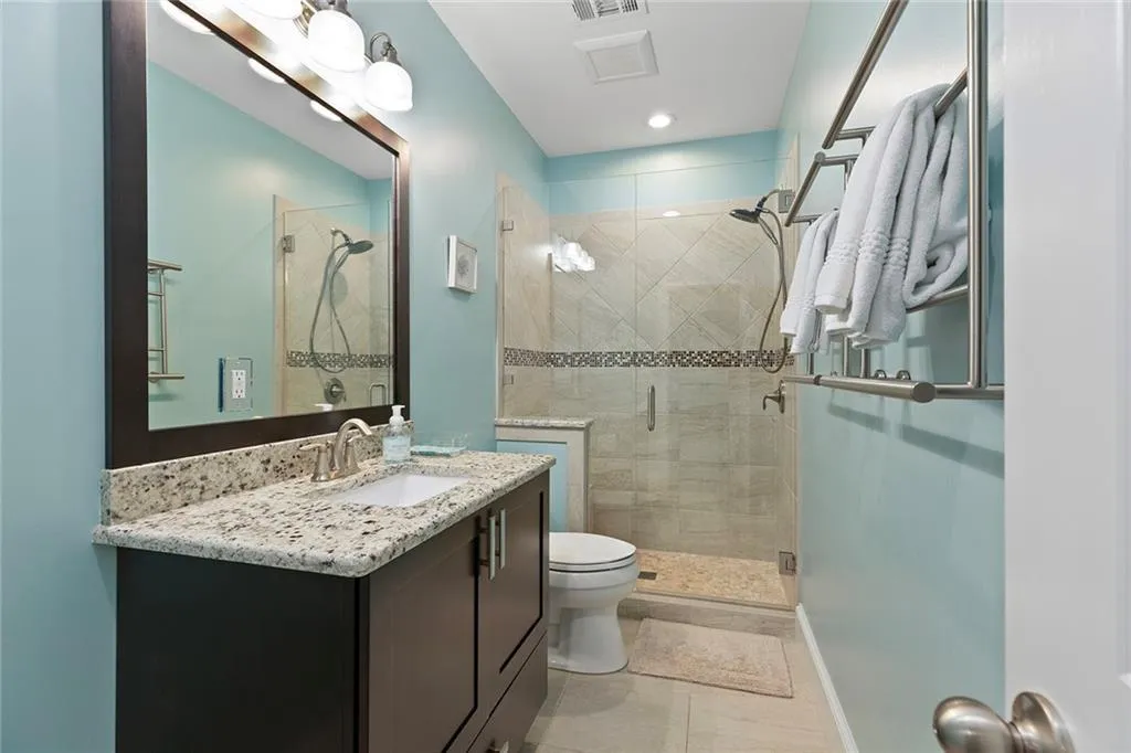 Bathroom featuring a shower with shower door, toilet, vanity, and tile patterned floors Bathroom featuring a shower with shower door, toilet, vanity, and tile patterned floors