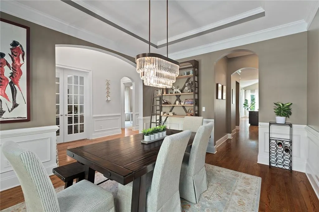 Dining room with ornamental molding, a raised ceiling, dark hardwood / wood-style flooring, and an inviting chandelier Dining room with ornamental molding, a raised ceiling, dark hardwood / wood-style flooring, and an inviting chandelier