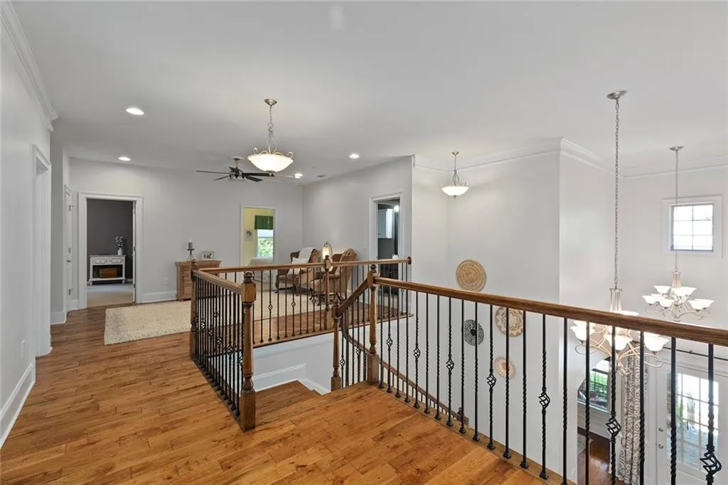 Hallway featuring hardwood / wood-style flooring, a chandelier, and ornamental molding Hallway featuring hardwood / wood-style flooring, a chandelier, and ornamental molding
