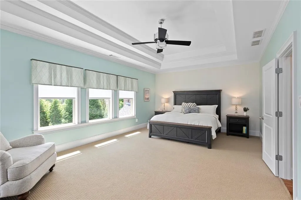 Carpeted bedroom with crown molding, a raised ceiling, and ceiling fan Carpeted bedroom with crown molding, a raised ceiling, and ceiling fan
