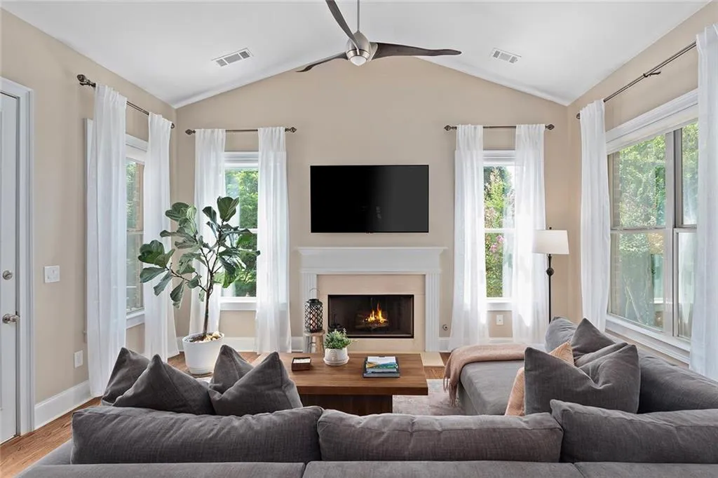 Living room with a fireplace, lofted ceiling, hardwood / wood-style floors, and ceiling fan Living room with a fireplace, lofted ceiling, hardwood / wood-style floors, and ceiling fan