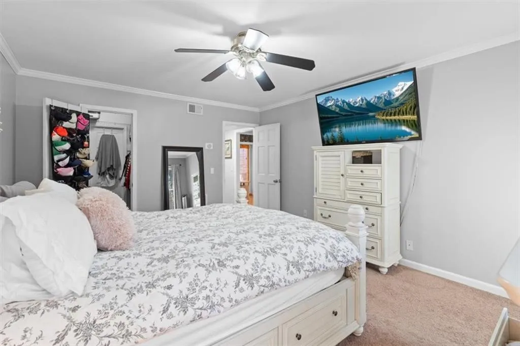 Bedroom featuring crown molding, light colored carpet, ceiling fan, and a closet