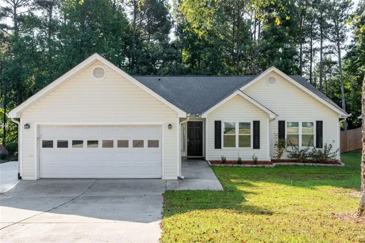 Single-story residence featuring light-colored siding, a dark shingle roof, and a two-car garage with panel windows