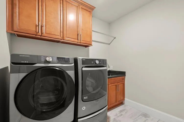 Clothes washing area with washing machine and dryer, light hardwood / wood-style floors, and cabinets