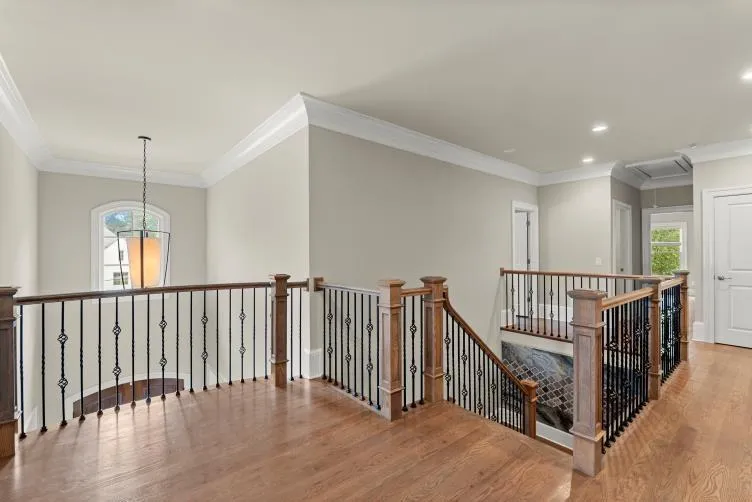 Hall with crown molding, an inviting chandelier, and hardwood / wood-style floors