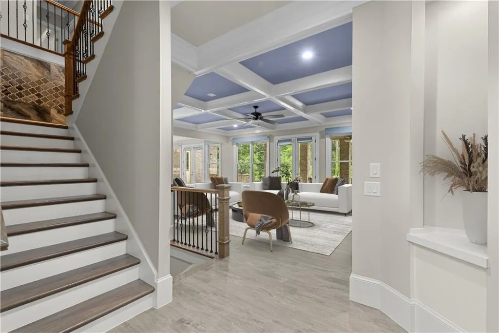Living room featuring coffered ceiling, beamed ceiling, light hardwood / wood-style floors, and ceiling fan