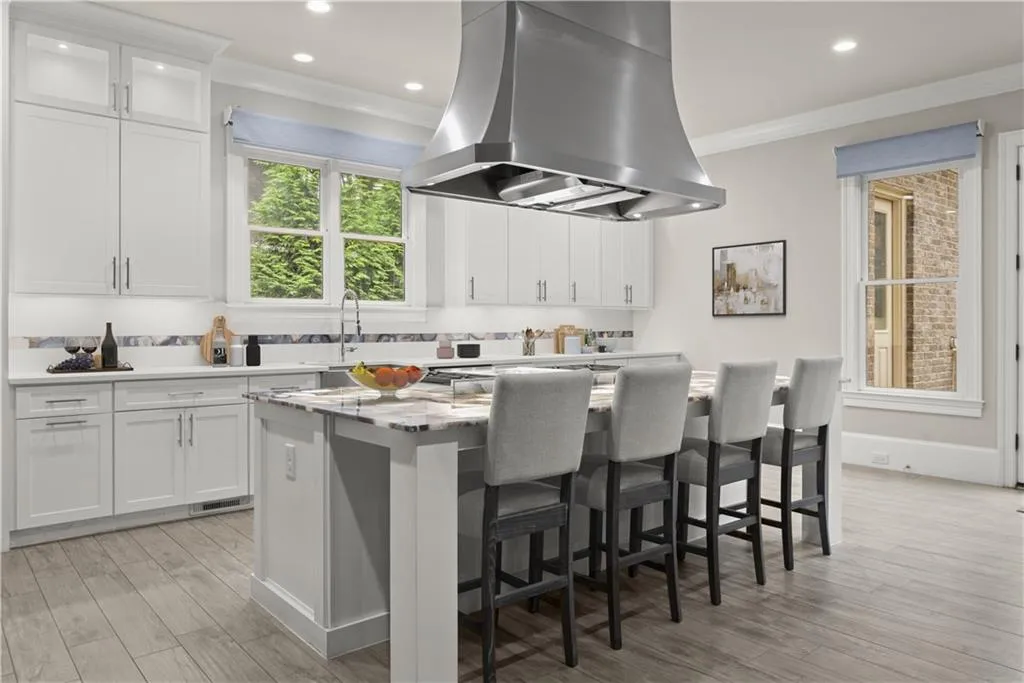 Kitchen with light hardwood / wood-style flooring, island exhaust hood, a center island, and white cabinetry