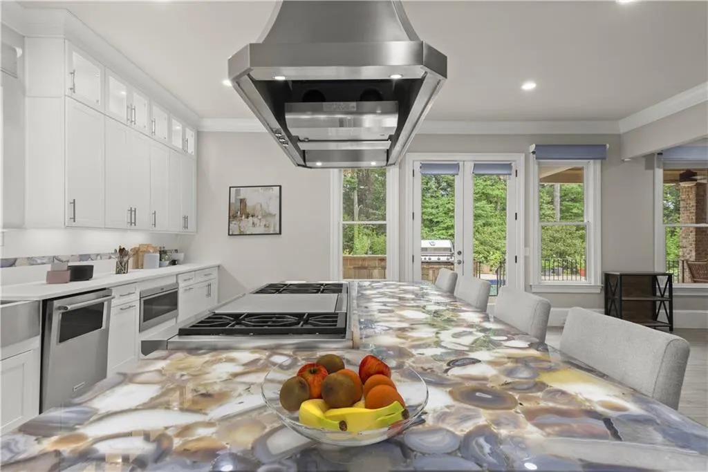 Kitchen with appliances with stainless steel finishes, island range hood, crown molding, and white cabinets
