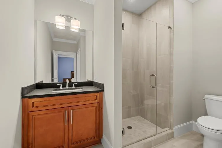 Bathroom featuring ornamental molding, tile floors, a shower with door, vanity, and toilet