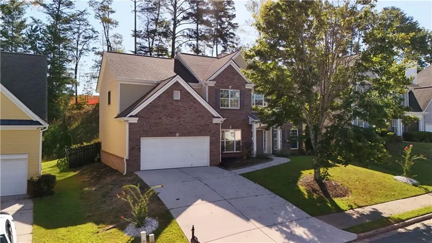 Traditional-style exterior featuring brick and siding, a two-car garage, mature front yard landscaping, and a paved driveway