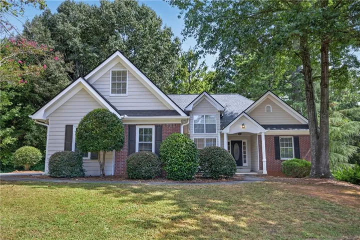 Front exterior featuring a brick and siding facade, multiple gables, a covered entry, and mature landscaping