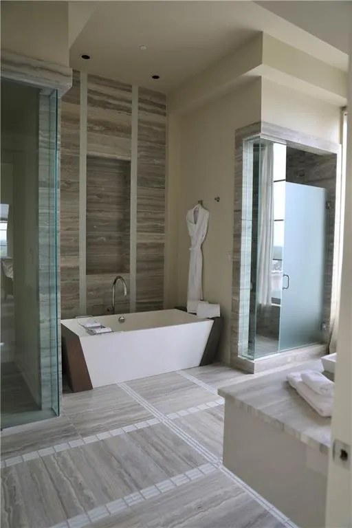 Bathroom featuring tile walls and independent shower and bath