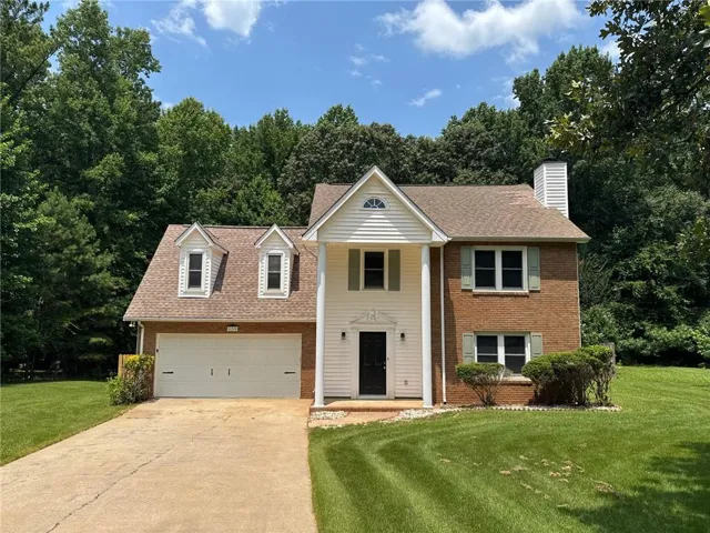 Traditional brick and siding exterior with a two-car garage, concrete driveway, and front entry porch with columns