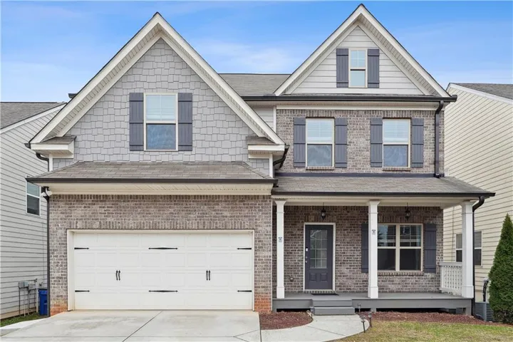 Brick and shingle exterior with white trim, featuring a covered front porch with white columns, a two-car garage, and dark window shutters