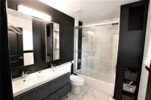 Full bathroom with enclosed tub / shower combo, tile patterned floors, toilet, and vanity