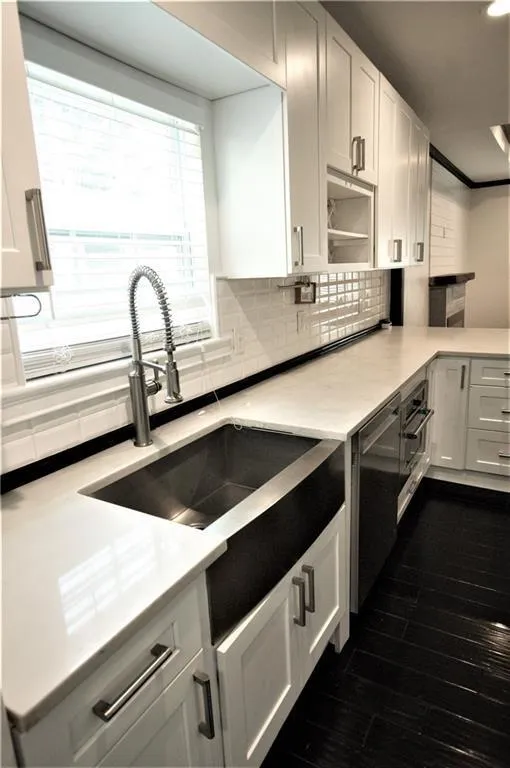 Kitchen with sink, dishwasher, dark hardwood / wood-style floors, tasteful backsplash, and white cabinets
