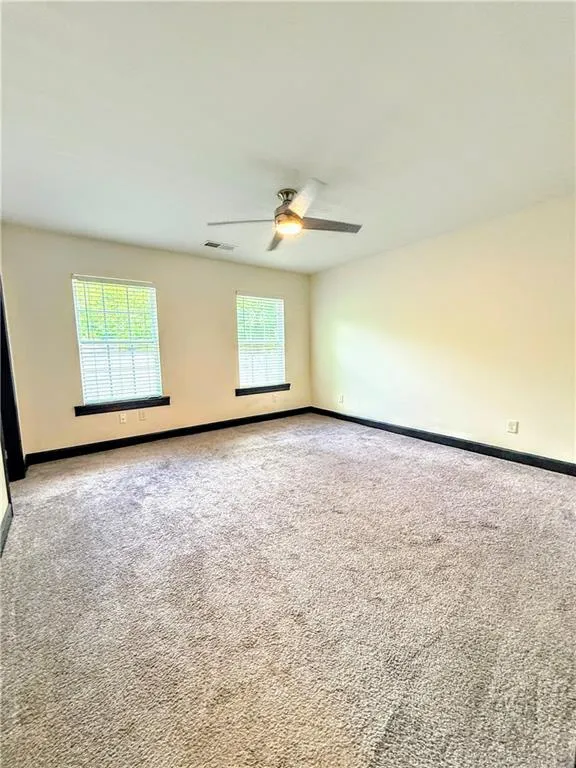 Carpeted empty room with a ceiling fan and baseboards