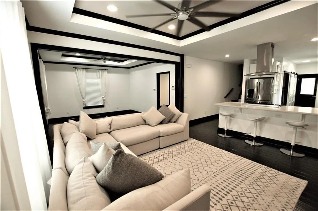 Living room featuring dark hardwood / wood-style floors, a raised ceiling, and ceiling fan