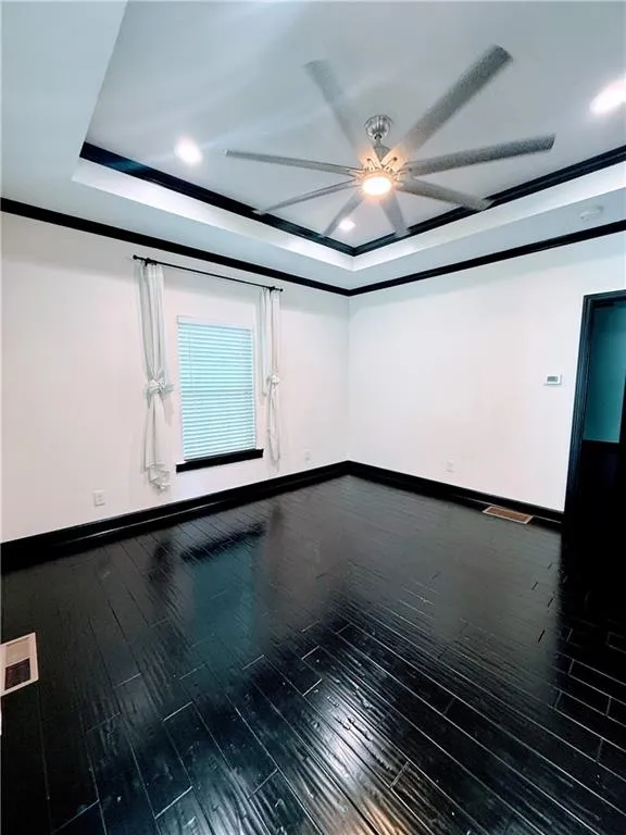 Unfurnished room with a ceiling fan, a raised ceiling, baseboards, dark wood-style floors, and recessed lighting
