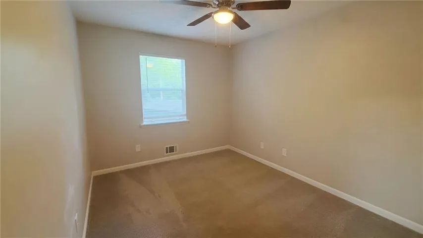 Neutral wall paint, carpet flooring, window with blinds, and a ceiling fan with integrated lighting