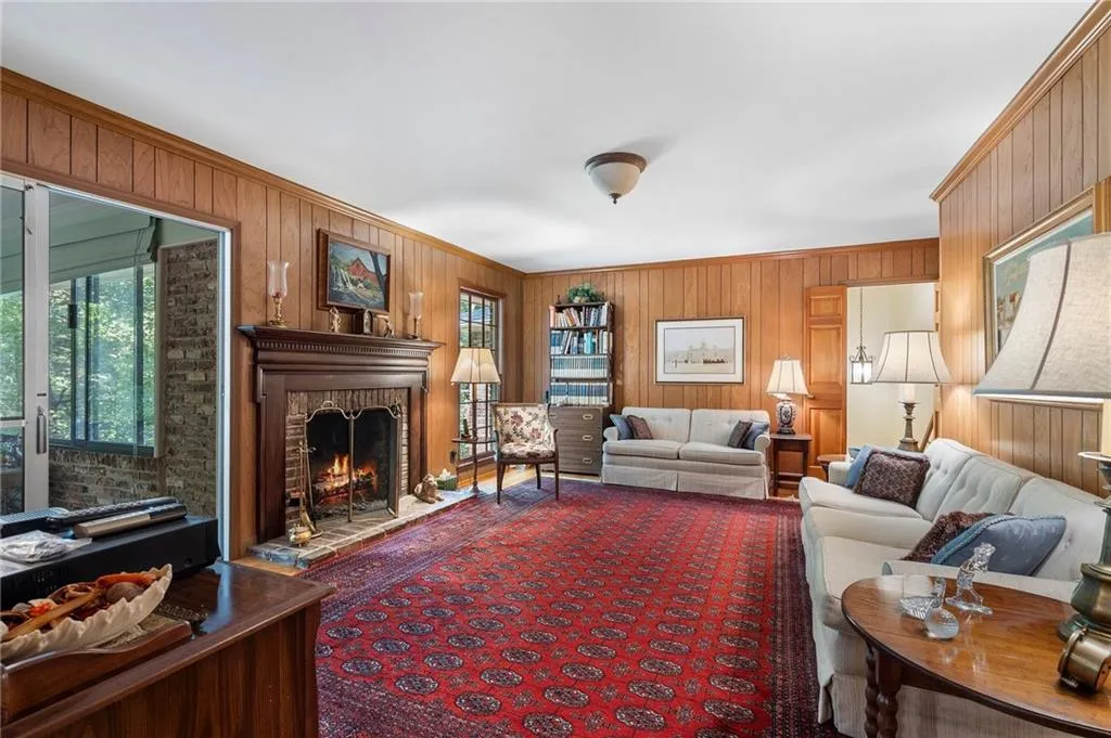 Living room featuring wooden walls, a fireplace, and crown molding