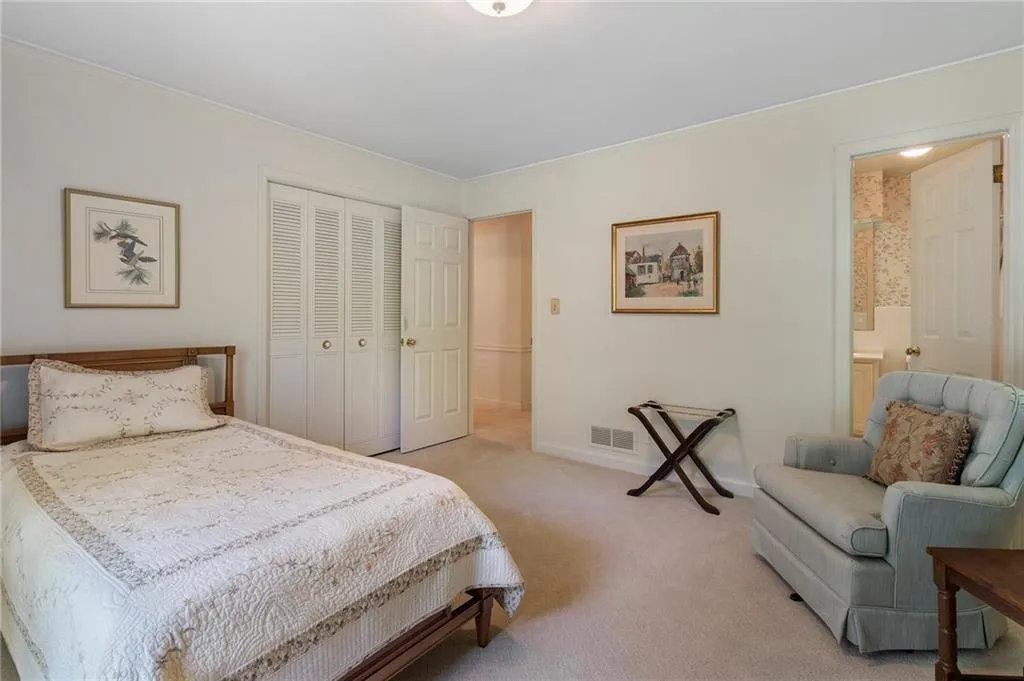 Bedroom featuring light carpet, ornamental molding, a closet, and ensuite bathroom