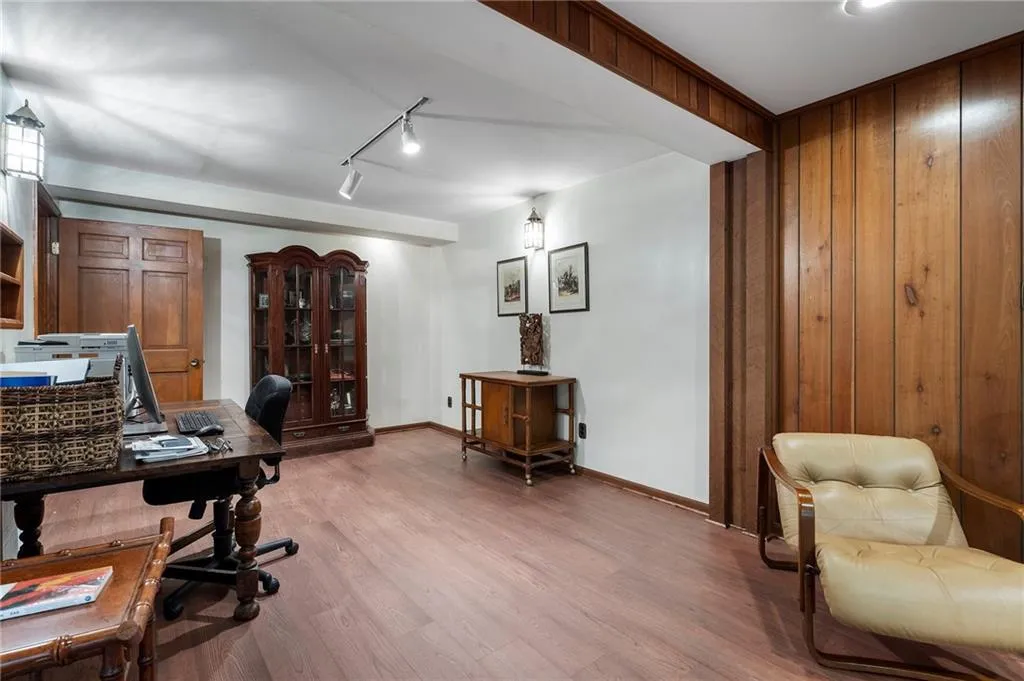 Office with wood walls, light wood-type flooring, and track lighting