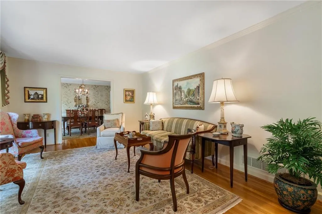 Living room with light hardwood / wood-style floors, crown molding, and an inviting chandelier