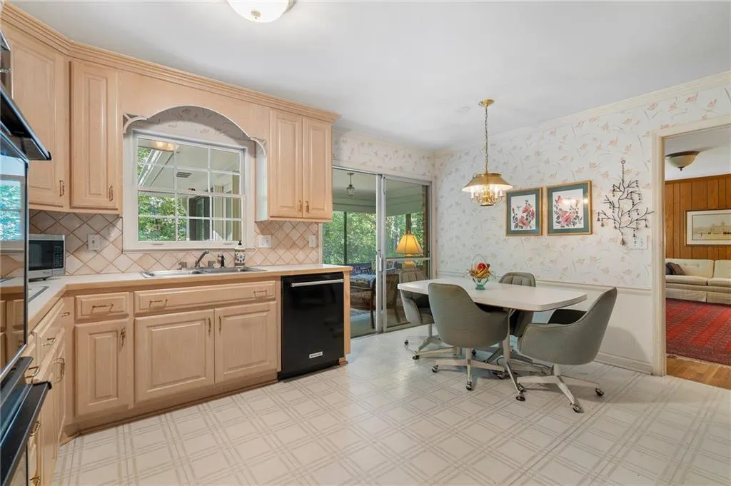 Kitchen with light brown cabinets, sink, decorative light fixtures, black dishwasher, and crown molding