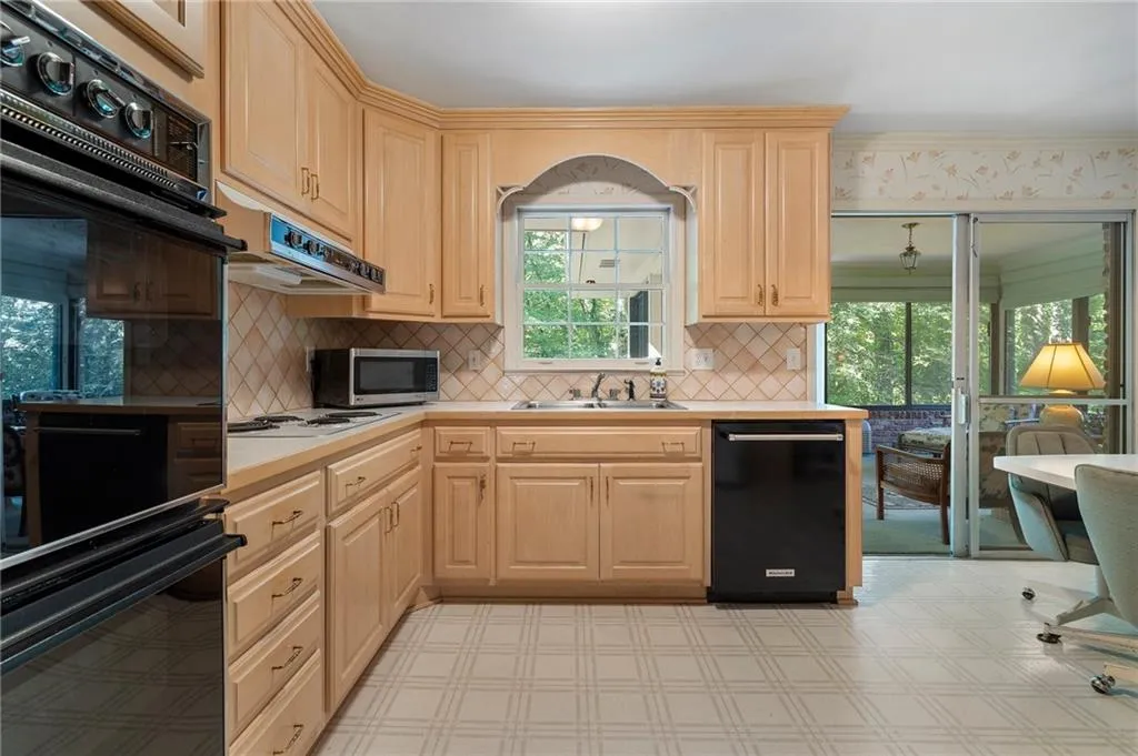 Kitchen with light brown cabinets, a wealth of natural light, and black appliances