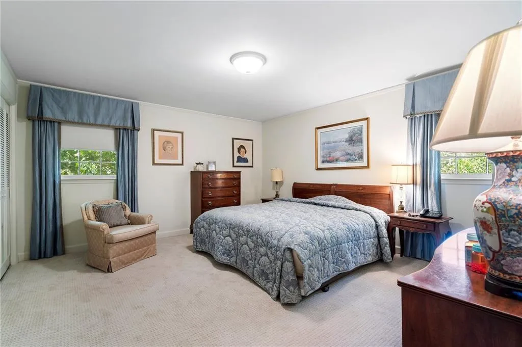 Bedroom with light colored carpet, ornamental molding, and multiple windows