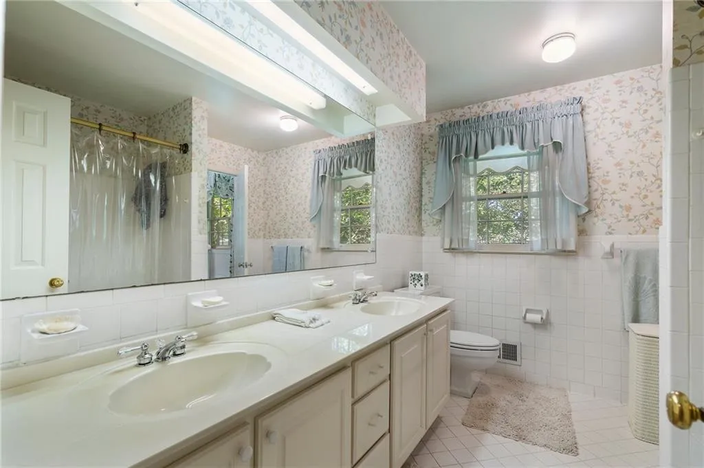 Bathroom with vanity, curtained shower, tile patterned floors, tile walls, and toilet