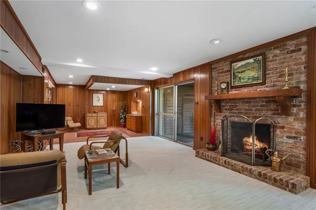 Carpeted basement living room featuring a fireplace and wooden walls