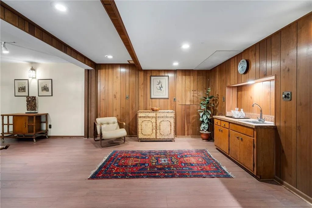 Basement Living area featuring wet bar, wooden walls, and light hardwood / wood-style floors.