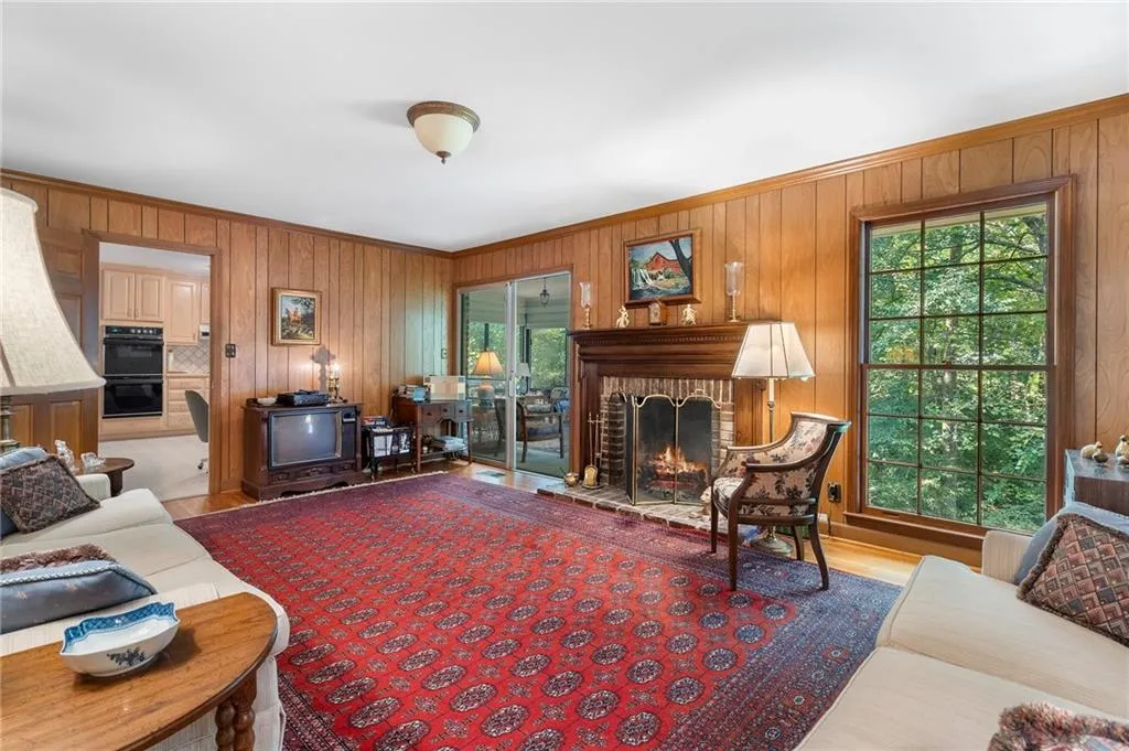 Living room with a fireplace, wood walls, and a healthy amount of sunlight