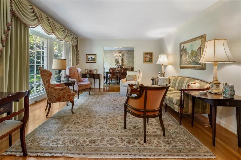 Living area with wood-type flooring, crown molding, an inviting chandelier, and plenty of natural light