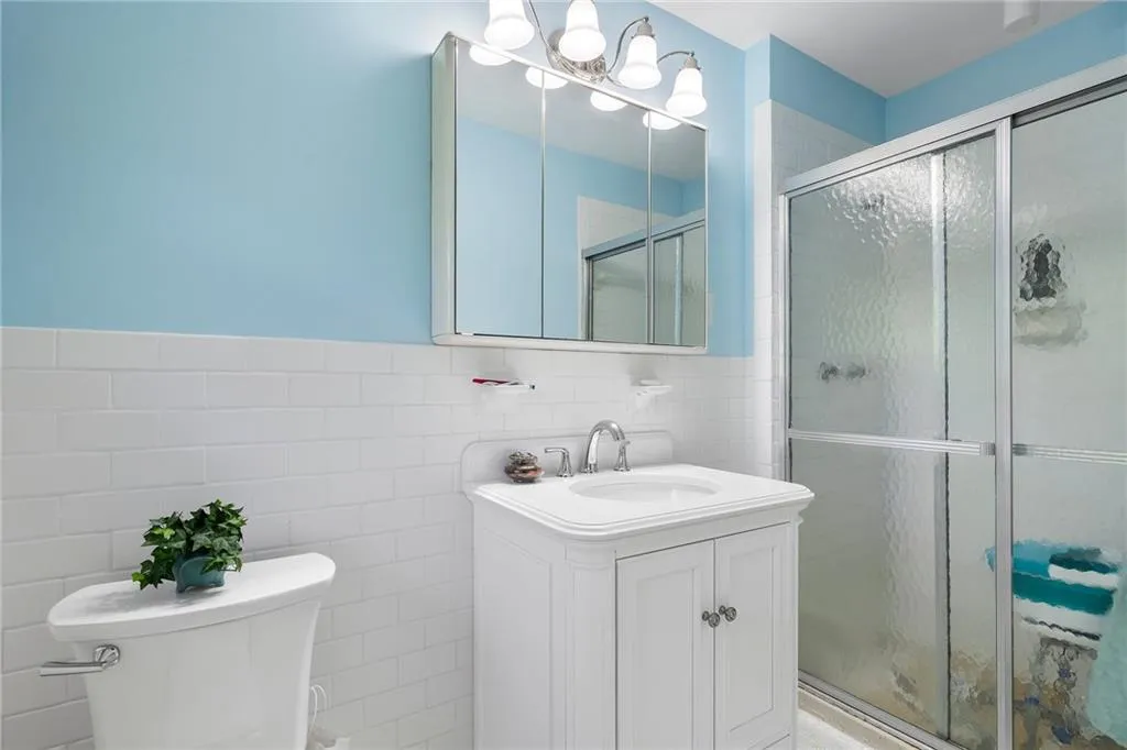 Bathroom with walk in shower, tile walls, vanity, and toilet